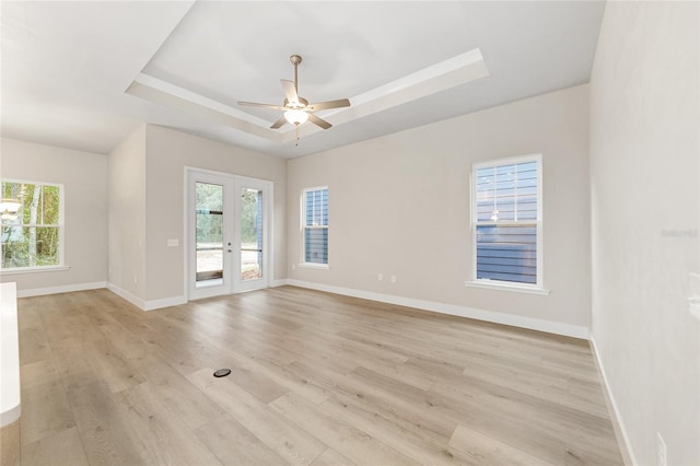 spare room featuring ceiling fan, a raised ceiling, light wood-type flooring, and french doors