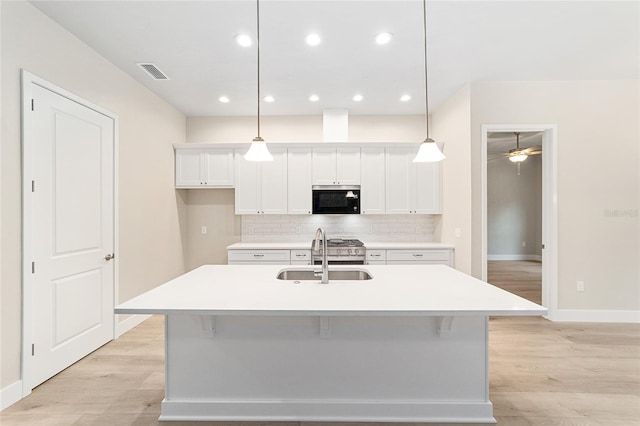 kitchen featuring pendant lighting, sink, and a kitchen island with sink