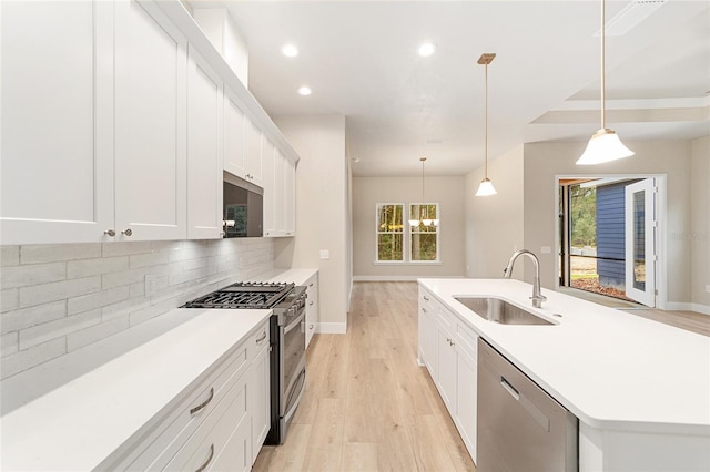 kitchen featuring appliances with stainless steel finishes, tasteful backsplash, sink, decorative light fixtures, and white cabinets