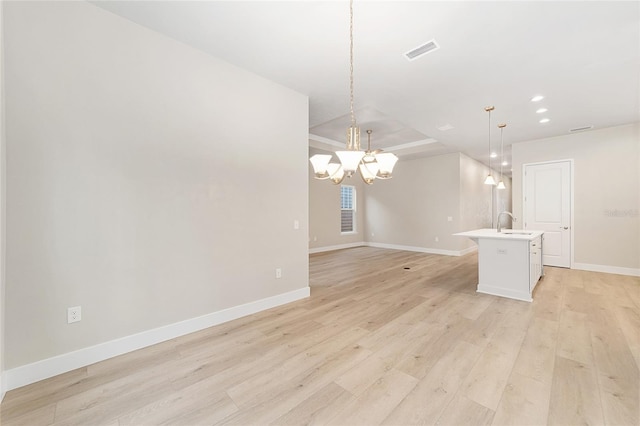 unfurnished living room featuring a raised ceiling, light hardwood / wood-style flooring, an inviting chandelier, and sink