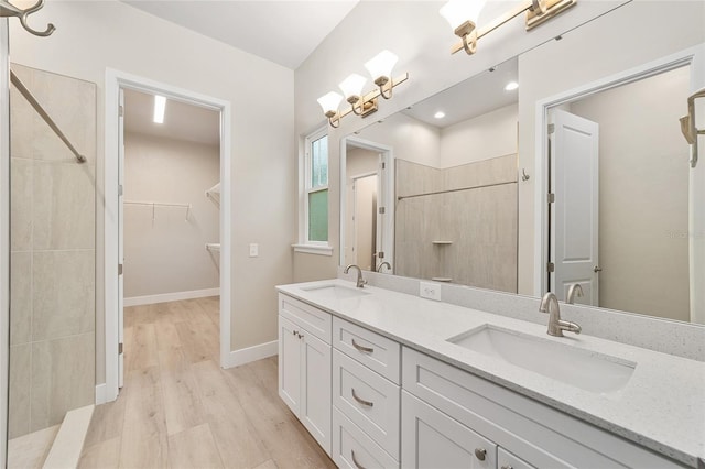 bathroom with vanity, a tile shower, and wood-type flooring