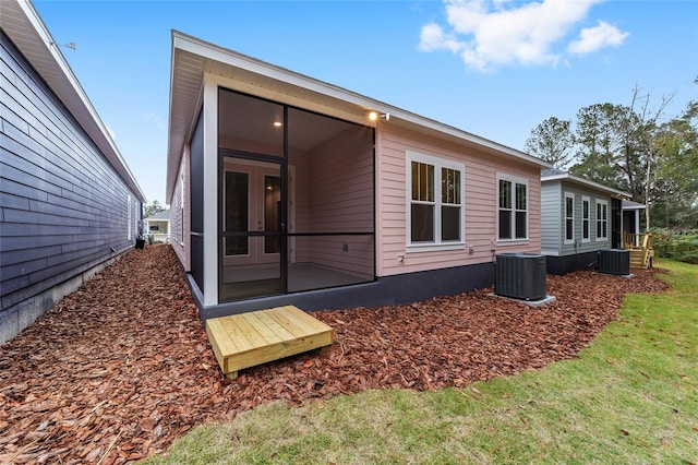 back of property with central AC, a sunroom, and a yard