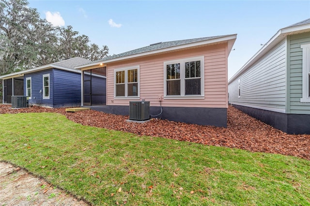 back of house featuring a sunroom, central air condition unit, and a lawn