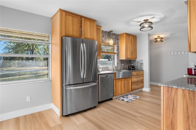 kitchen featuring pendant lighting, decorative backsplash, dark stone countertops, appliances with stainless steel finishes, and light hardwood / wood-style floors