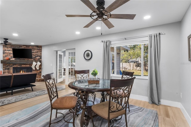 dining space with ceiling fan, a fireplace, and light hardwood / wood-style flooring