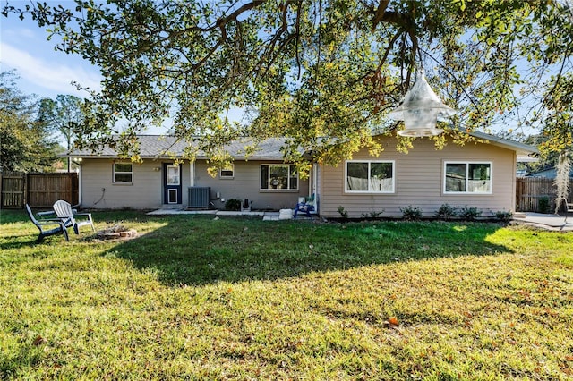 rear view of house with central AC unit and a yard