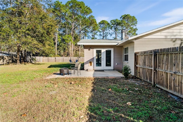 rear view of house featuring french doors, an outdoor fire pit, a patio area, and a lawn