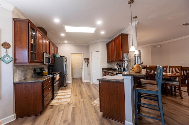 kitchen featuring sink, hanging light fixtures, stainless steel appliances, a kitchen breakfast bar, and kitchen peninsula