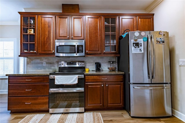 kitchen with stone counters, stainless steel appliances, ornamental molding, decorative backsplash, and light wood-type flooring