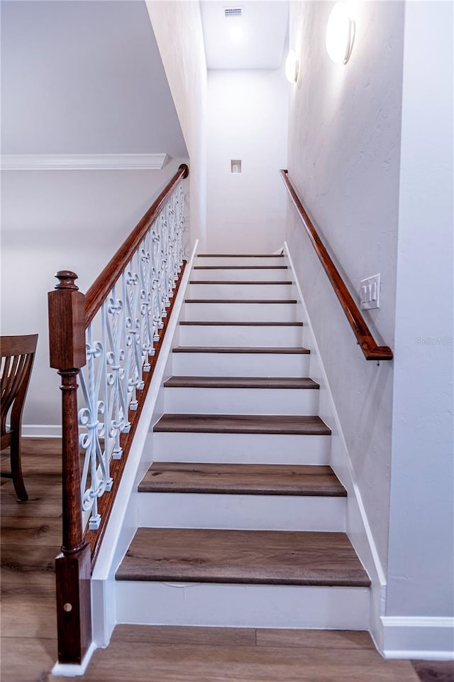 staircase featuring hardwood / wood-style floors and crown molding