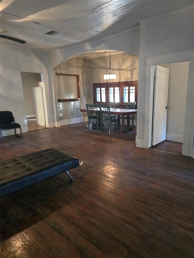 unfurnished dining area with ceiling fan with notable chandelier and dark wood-type flooring