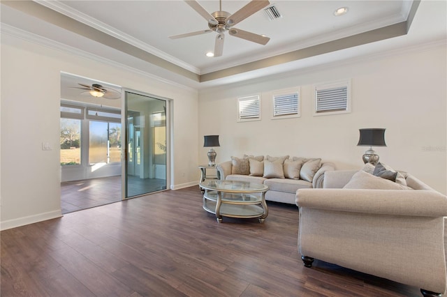 living room featuring a raised ceiling, crown molding, and dark wood-type flooring