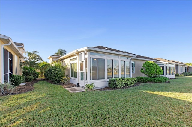 rear view of property with a sunroom and a yard