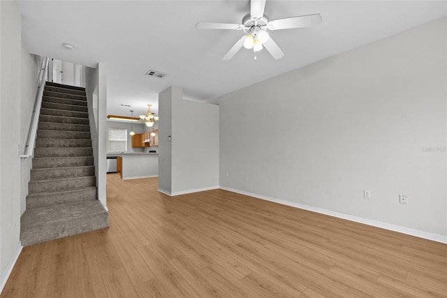 unfurnished living room with ceiling fan with notable chandelier and light wood-type flooring