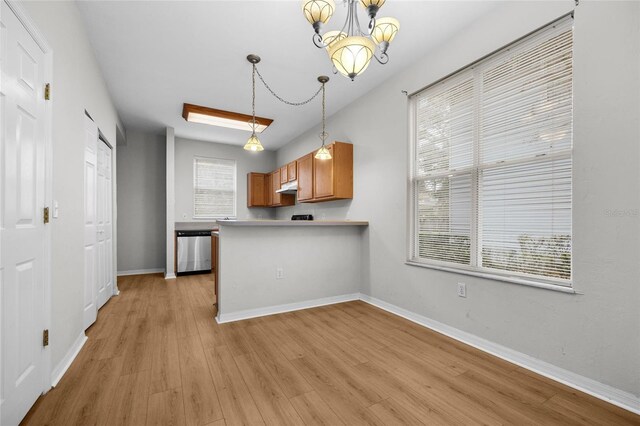 kitchen with hanging light fixtures, an inviting chandelier, stainless steel dishwasher, kitchen peninsula, and light wood-type flooring