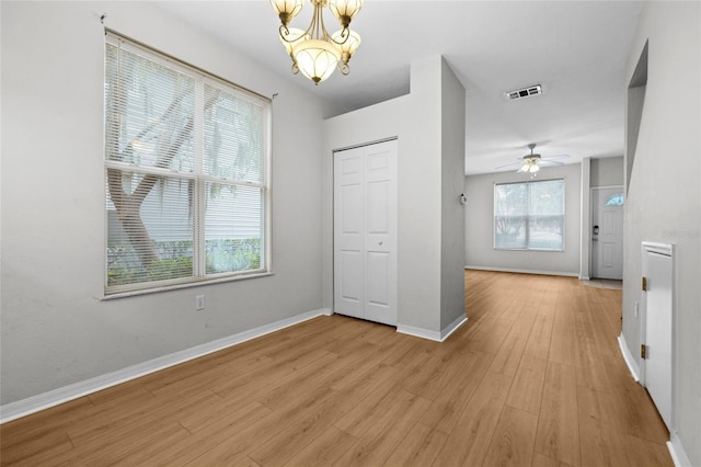 interior space featuring ceiling fan with notable chandelier and light hardwood / wood-style flooring