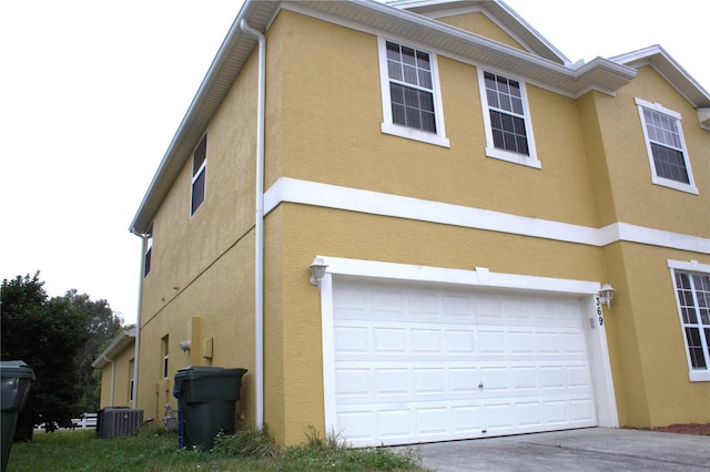 view of side of home with a garage and central AC unit