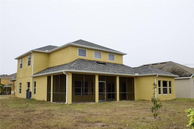 rear view of house featuring a sunroom and a lawn