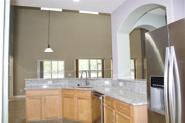 kitchen featuring tile patterned floors, sink, hanging light fixtures, light stone countertops, and stainless steel appliances