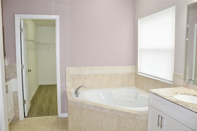 bathroom with vanity, tile patterned floors, a healthy amount of sunlight, and tiled tub