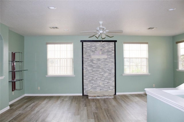 unfurnished bedroom featuring ceiling fan, wood-type flooring, a textured ceiling, and multiple windows