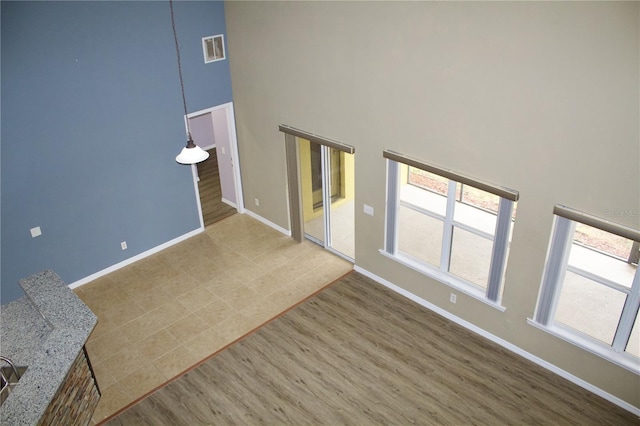 unfurnished living room featuring hardwood / wood-style floors and a towering ceiling