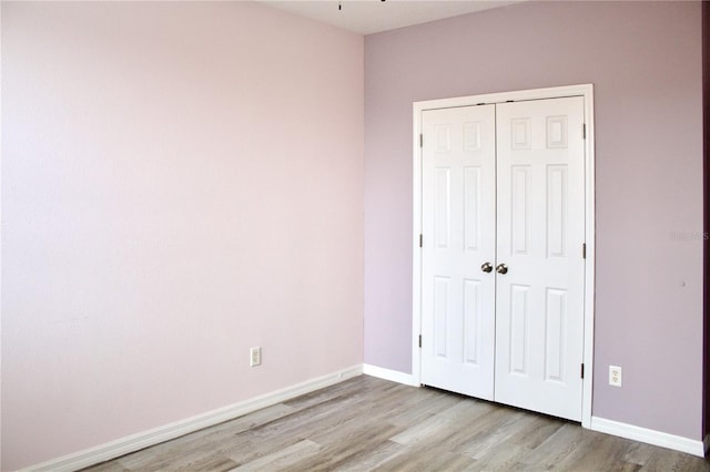 unfurnished bedroom featuring light hardwood / wood-style flooring and a closet