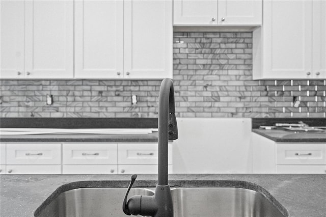 kitchen featuring tasteful backsplash, white cabinetry, and sink