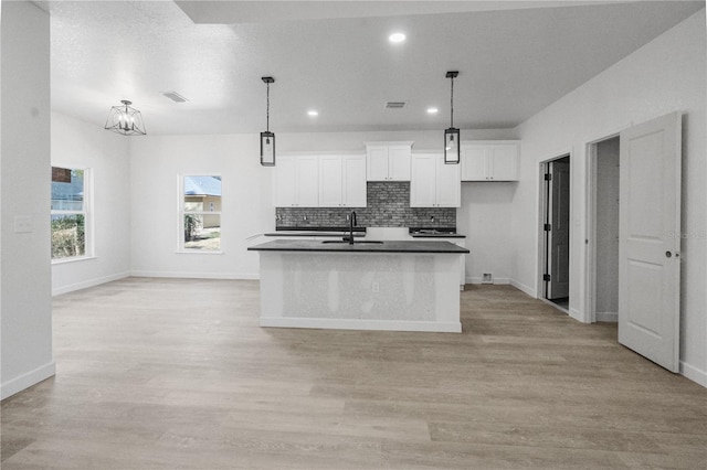 kitchen with pendant lighting, a center island with sink, sink, light hardwood / wood-style floors, and white cabinetry