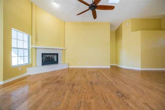 unfurnished living room with hardwood / wood-style floors, ceiling fan, and a tiled fireplace