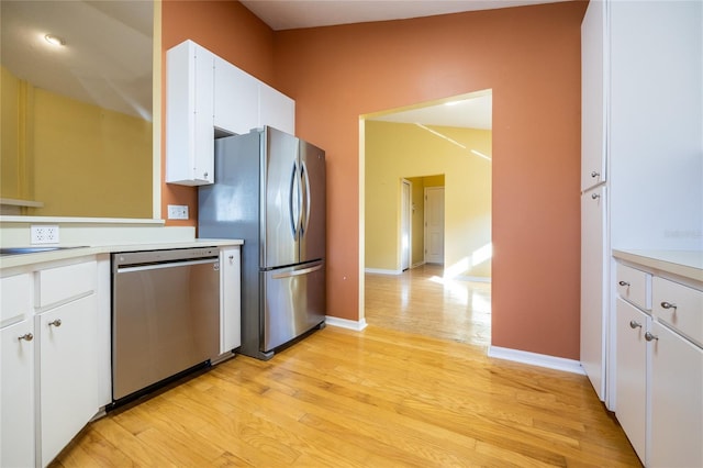 kitchen with sink, stainless steel appliances, light hardwood / wood-style flooring, lofted ceiling, and white cabinets