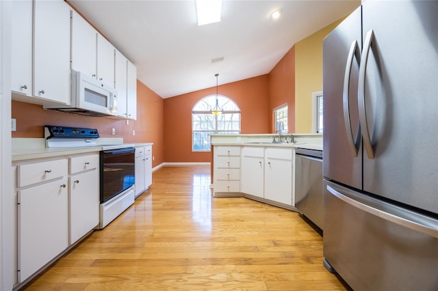 kitchen with pendant lighting, lofted ceiling, white cabinets, appliances with stainless steel finishes, and light hardwood / wood-style floors