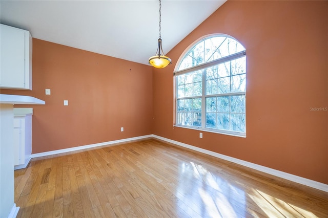 unfurnished dining area featuring light hardwood / wood-style floors and vaulted ceiling