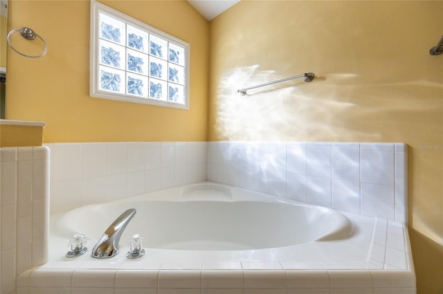 bathroom with tiled bath and lofted ceiling