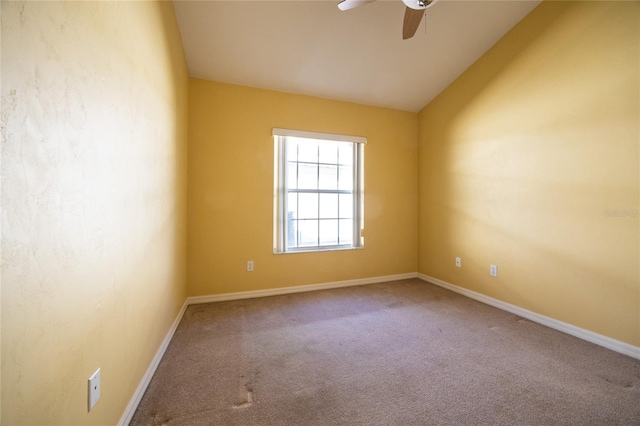 carpeted spare room featuring ceiling fan and vaulted ceiling