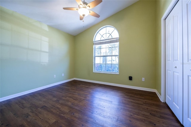 unfurnished bedroom with ceiling fan, dark hardwood / wood-style flooring, lofted ceiling, and a closet