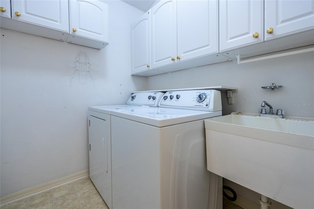 clothes washing area featuring cabinets, washing machine and clothes dryer, and sink