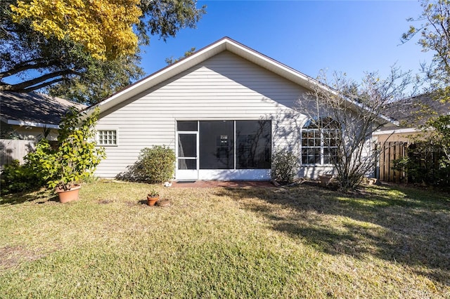 rear view of house with a lawn and a sunroom