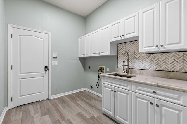 laundry area featuring light wood finished floors, a sink, hookup for a washing machine, electric dryer hookup, and cabinet space