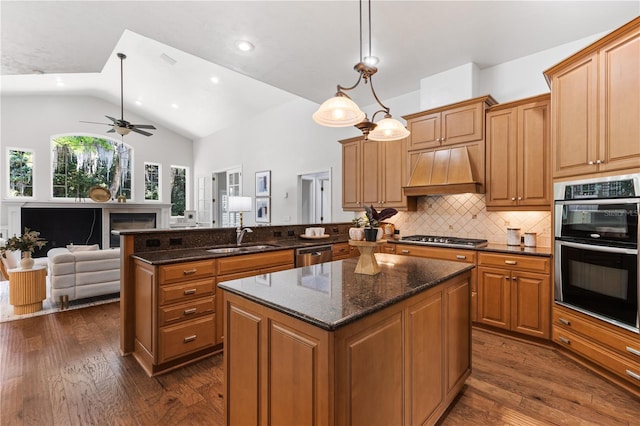 kitchen with a sink, a kitchen island, a peninsula, appliances with stainless steel finishes, and custom range hood
