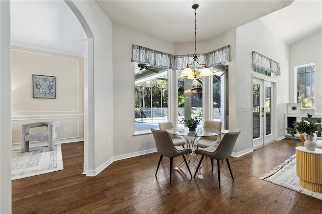 dining area with baseboards, wood finished floors, arched walkways, and a notable chandelier