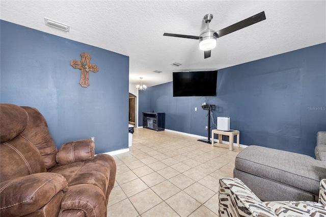 living room featuring a textured ceiling, light tile patterned floors, and ceiling fan with notable chandelier