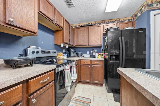 kitchen with light tile patterned flooring, a textured ceiling, black fridge, and electric stove