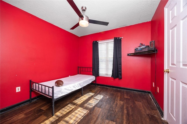 bedroom featuring ceiling fan, dark hardwood / wood-style flooring, and a textured ceiling