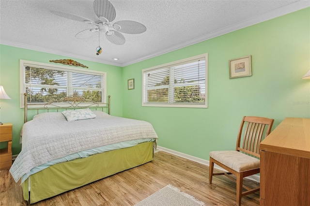 bedroom featuring ceiling fan, light wood-type flooring, ornamental molding, and a textured ceiling