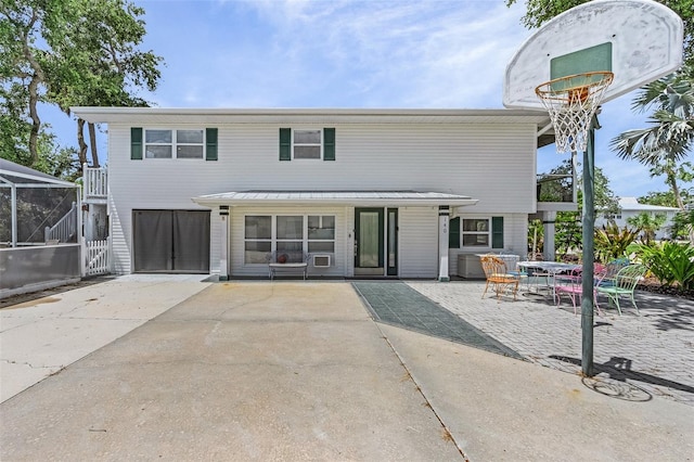 rear view of property with glass enclosure and a patio