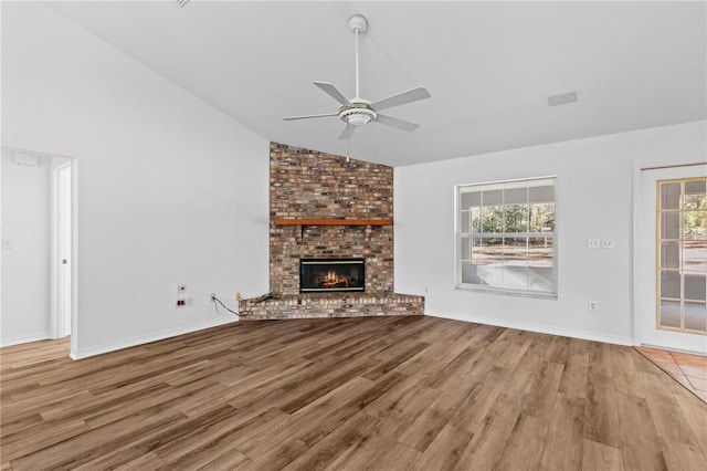 unfurnished living room featuring a brick fireplace, light hardwood / wood-style floors, ceiling fan, and vaulted ceiling