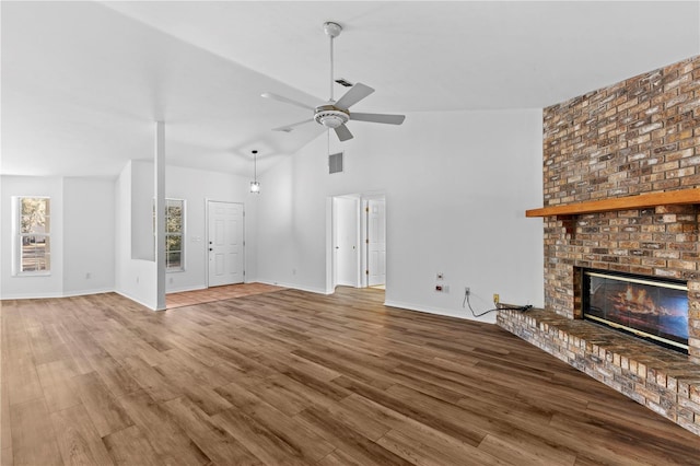 unfurnished living room with vaulted ceiling, ceiling fan, hardwood / wood-style floors, and a brick fireplace