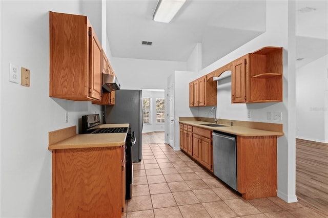 kitchen featuring light tile patterned flooring, lofted ceiling, range with gas stovetop, stainless steel dishwasher, and sink