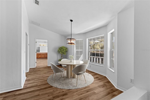 dining room with hardwood / wood-style flooring, lofted ceiling, and an inviting chandelier